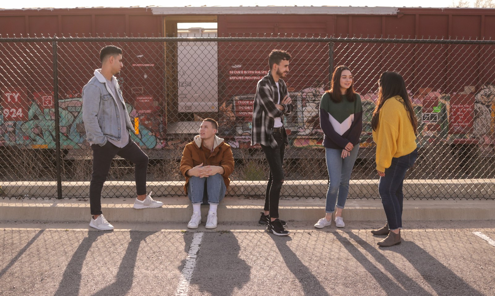 A group of young people chatting together by a fence