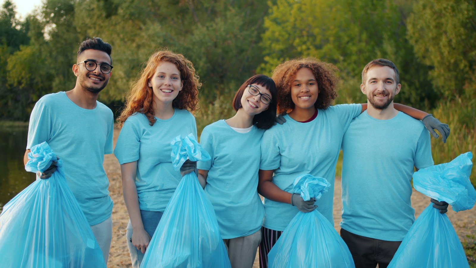 A group of young volunteers smiling together outdoors after a clean-up
